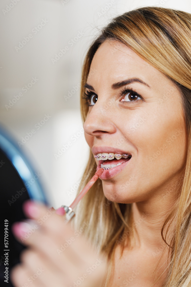 Woman With Braces Putting Lip Gloss Woman With Braces Putting Lip Gloss