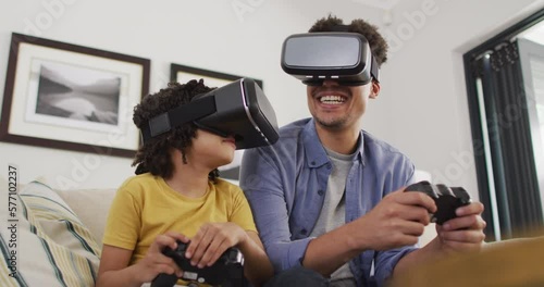 Happy biracial man and his son playing video games wearing vr headset photo