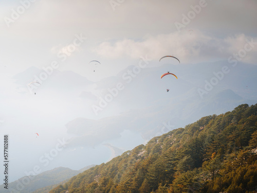 Paragliding in sky. Paraglider tandem flying over sea and mountains in cloudy day. view of paraglider and Blue Lagoon in Oludeniz, Turkey. Extreme sport. Landscape