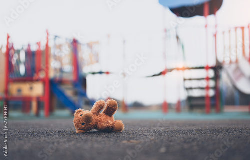 Fotografie Lost teddy bear toy lying don on playground floor in gloomy day,Lonely and sad b