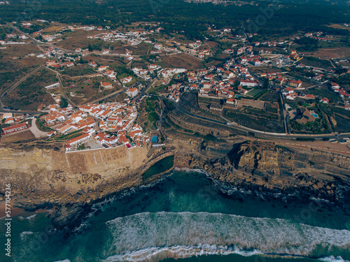 Aerial photos of Azenhas do Mar in Sintra, Portugal showcase a picturesque seaside village with white houses and a natural swimming pool, surrounded by dramatic cliffs and the sparkling Atlantic Ocean