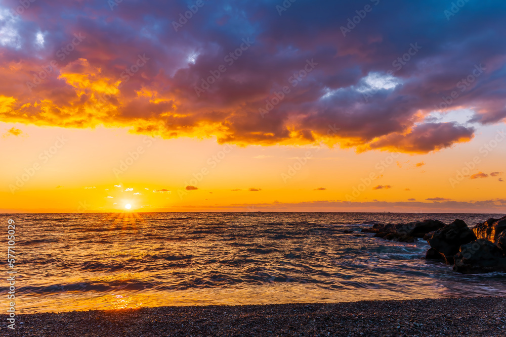 empty beach with surf during beautiful sunrise or sunset with surf, clouds and golden sun