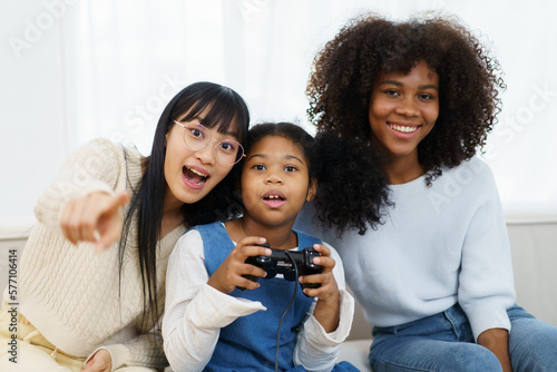 Concept of diversity in ethnic people spending a time together in a weekend. A diverse group and generation people relaxing and playing a video game together in living room.