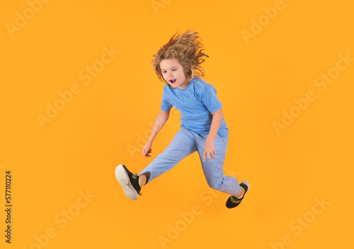 Kid boy 8-9 years old in t-shirt jump isolated on yellow background. Childhood lifestyle concept. Mock up copy space. Kid having fun, jumping.