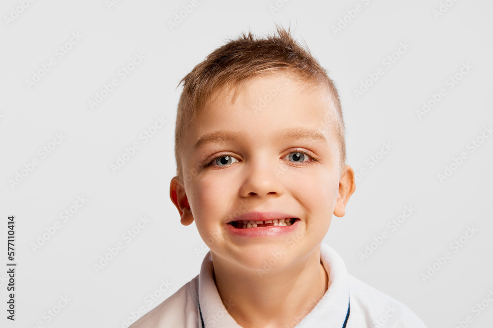 Close-up portrait of little emotional boy, kid, smiling, posing against grey studio background. Concept of childhood, game, friendship, activity, leisure time, retro style, fashion. Close-up portrait of little emotional boy, kid, smiling, posing against grey studio background. Concept of childhood, game, friendship, activity, leisure time, retro style, fashion.