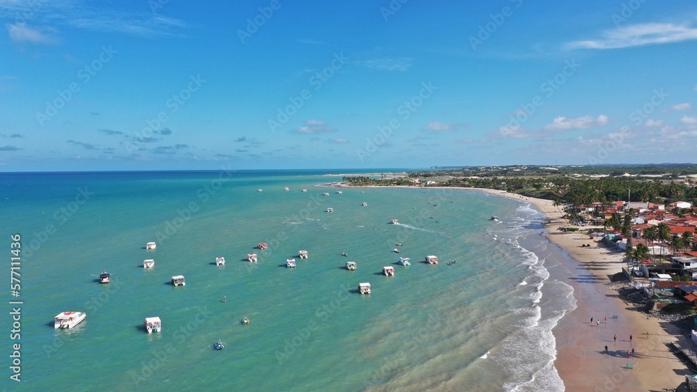 Wonderful view of a calm beach with turquoise warm waters with fishing boats and people sunbathing near Natal in Rio Grande do Norte State, Brazil 