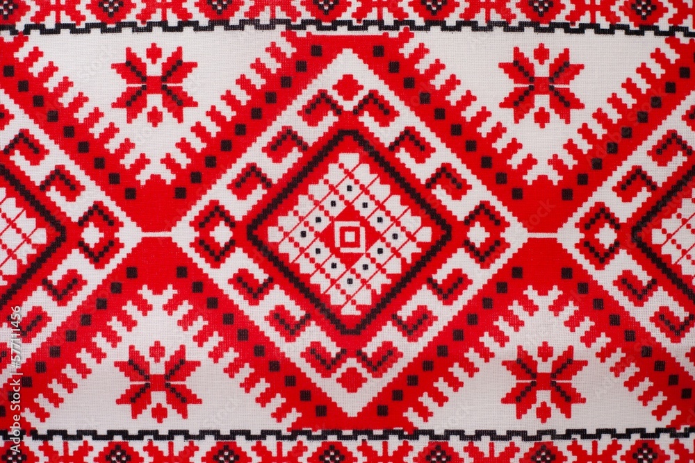 Embroidered fabric with red and black details on a white background, cubes and various mosaics as a decorative background Embroidered fabric with red and black details on a white background, cubes and various mosaics as a decorative background