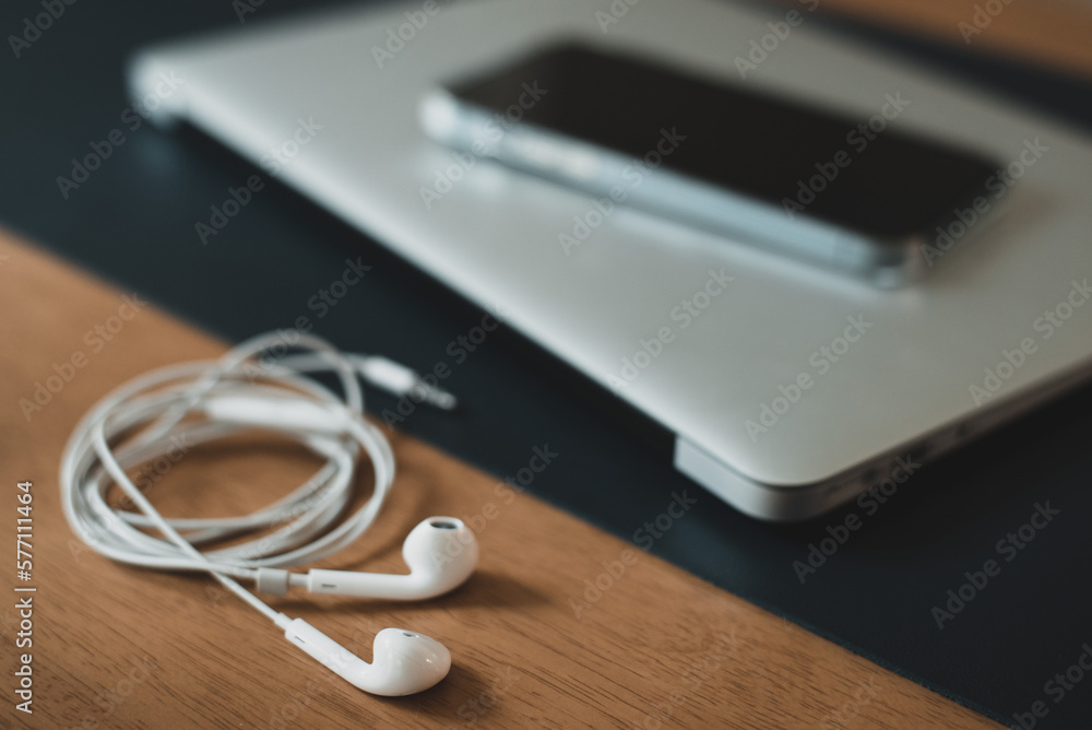 Laptop, headphones and smart phone lie on a wooden desk in the office. These electronic devices are for work, study and entertainment. Laptop, headphones and smart phone lie on a wooden desk in the office. These electronic devices are for work, study and entertainment.