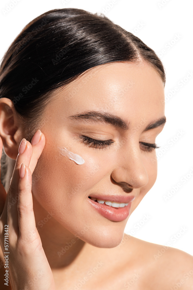 close up view of cheerful young woman applying face cream on cheek isolated on white. close up view of cheerful young woman applying face cream on cheek isolated on white.