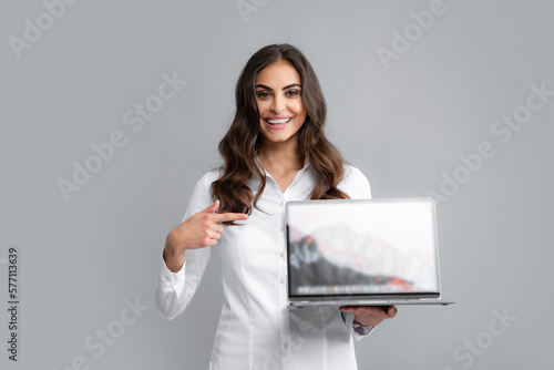 Business woman holding laptop with empty mock up screen for copy space. Portrait of young businesswoman using laptop computer isolated on gray background.