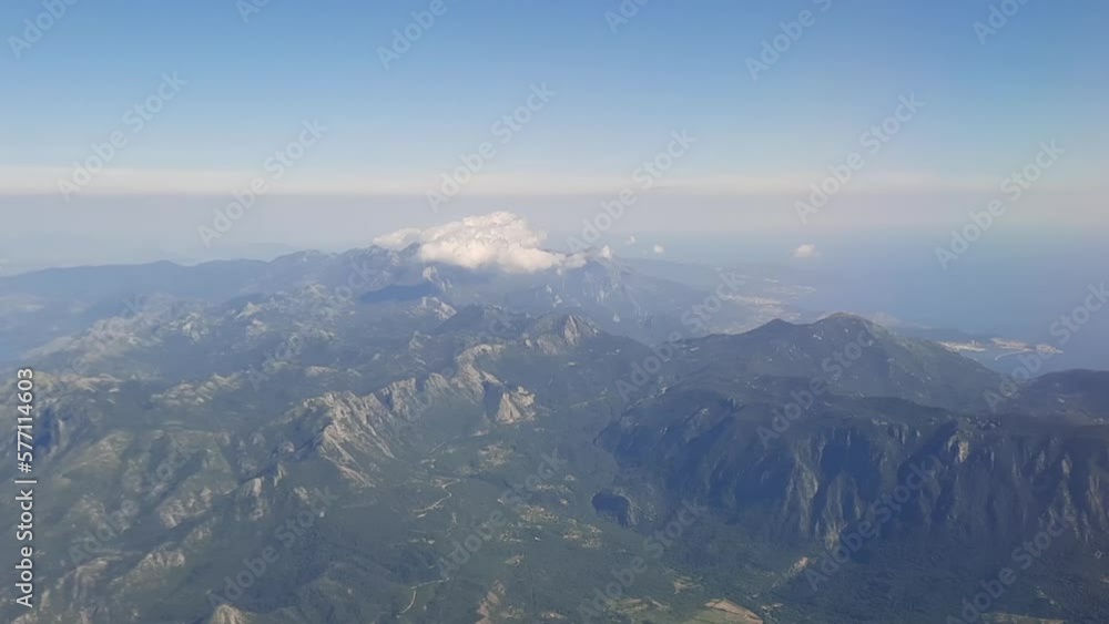 Aerial view of ground and mountain. Flight high through moving clouds on the sky. Looking of horizon out the window airplane seeing wonderful landscape and earth. Travel and transportation concept. Aerial view of ground and mountain. Flight high through moving clouds on the sky. Looking of horizon out the window airplane seeing wonderful landscape and earth. Travel and transportation concept.