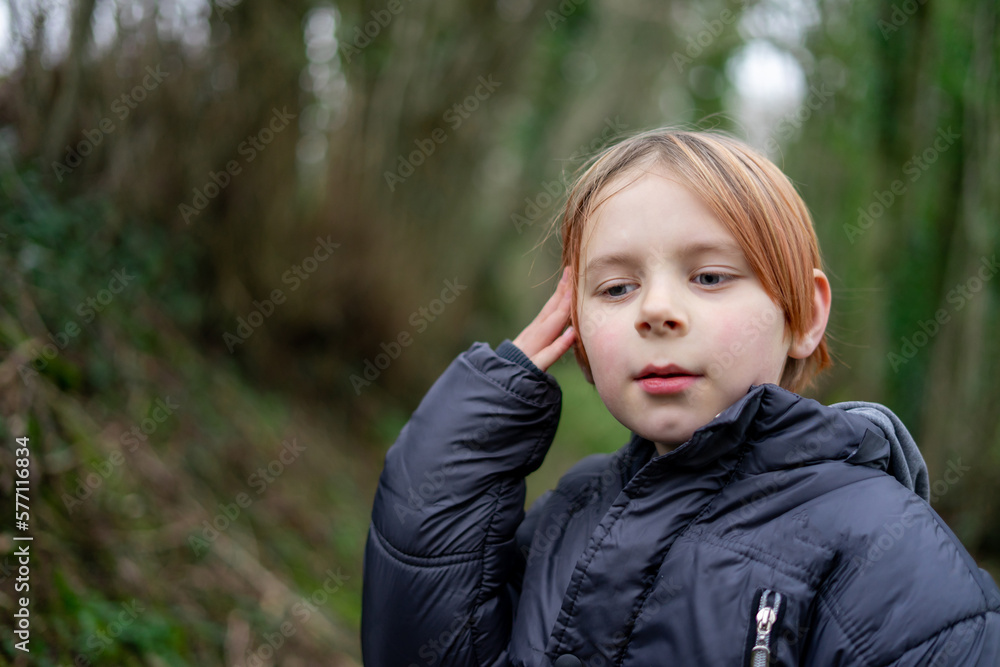 Young boy in outdoors thoughtfulness. A boy of eight ten years old in a warm jacket in the forest. Childish doubts, reflections concept. Young boy in outdoors thoughtfulness. A boy of eight ten years old in a warm jacket in the forest. Childish doubts, reflections concept.