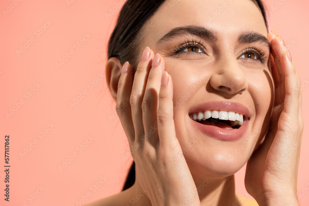 happy young woman touching soft cheeks and looking away isolated on pink. happy young woman touching soft cheeks and looking away isolated on pink.