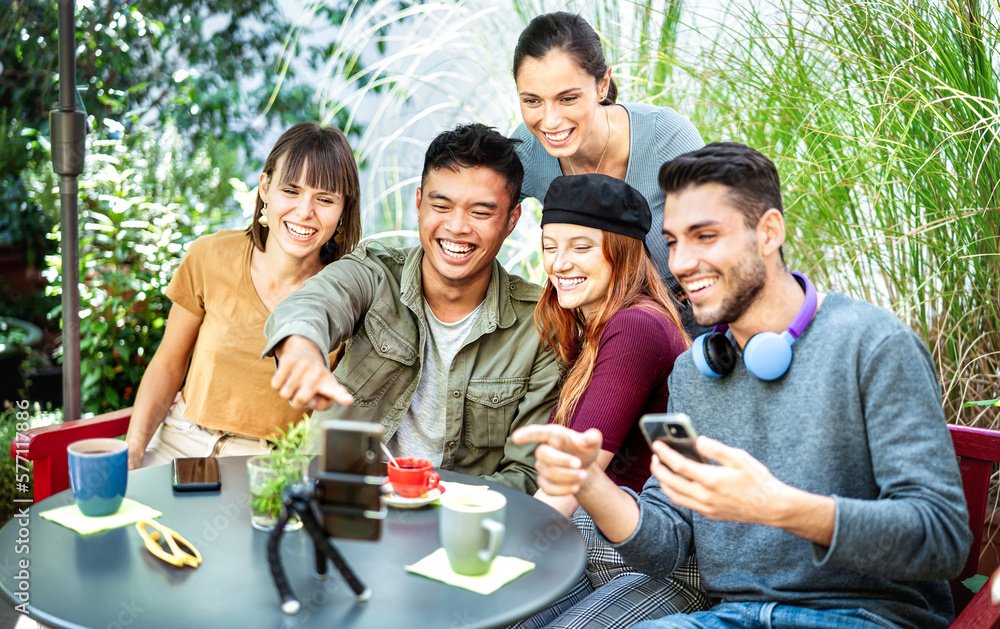 Obraz premium Young people sharing content on streaming platform at coworking cafeteria - Youth life style tech concept with happy milenial influencers having fun vlogging live feeds at coffee bar - Bright filter