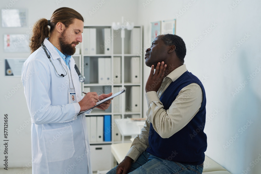 Obraz premium Mature male patient describing symptoms to endocrinologist making notes in document during medical consultation in clinics