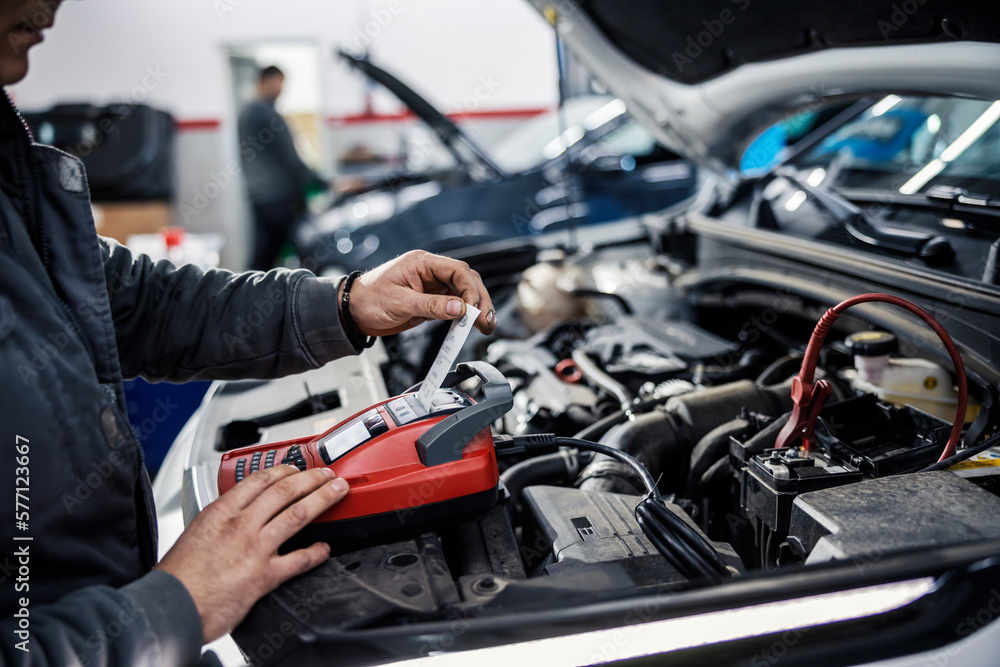 Close up of a car workshop worker doing car battery checkup with special device. Close up of a car workshop worker doing car battery checkup with special device.