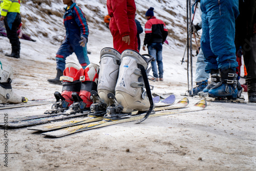 Low shot of sking boots on skis in snow showing crowd of people in winter wear playing in snow, sking, sliding, at snow point in lahul, manali solang a popular tourist spot during winters