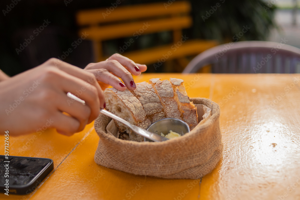 Caucasian woman hands eating bread garnishing with butter knife at restaurant table