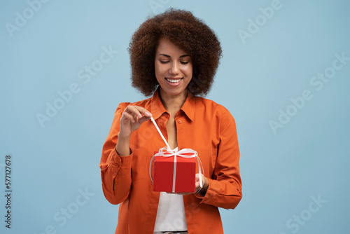 Slika na platnu Portrait of african american woman opening gift box, unwrapping birthday present