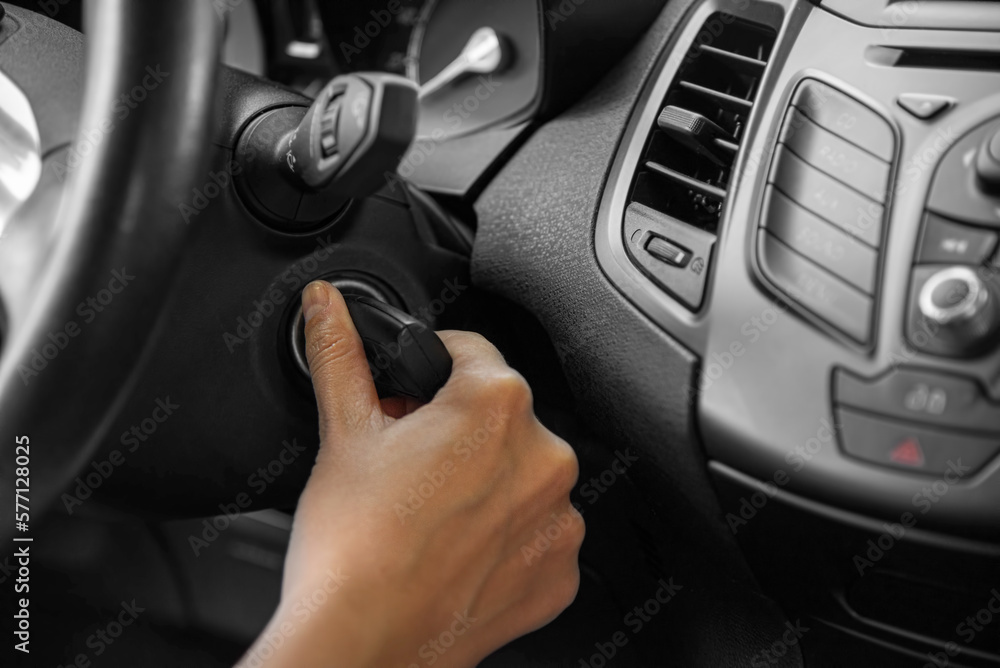 A woman's hand starts the car with a key, close-up.