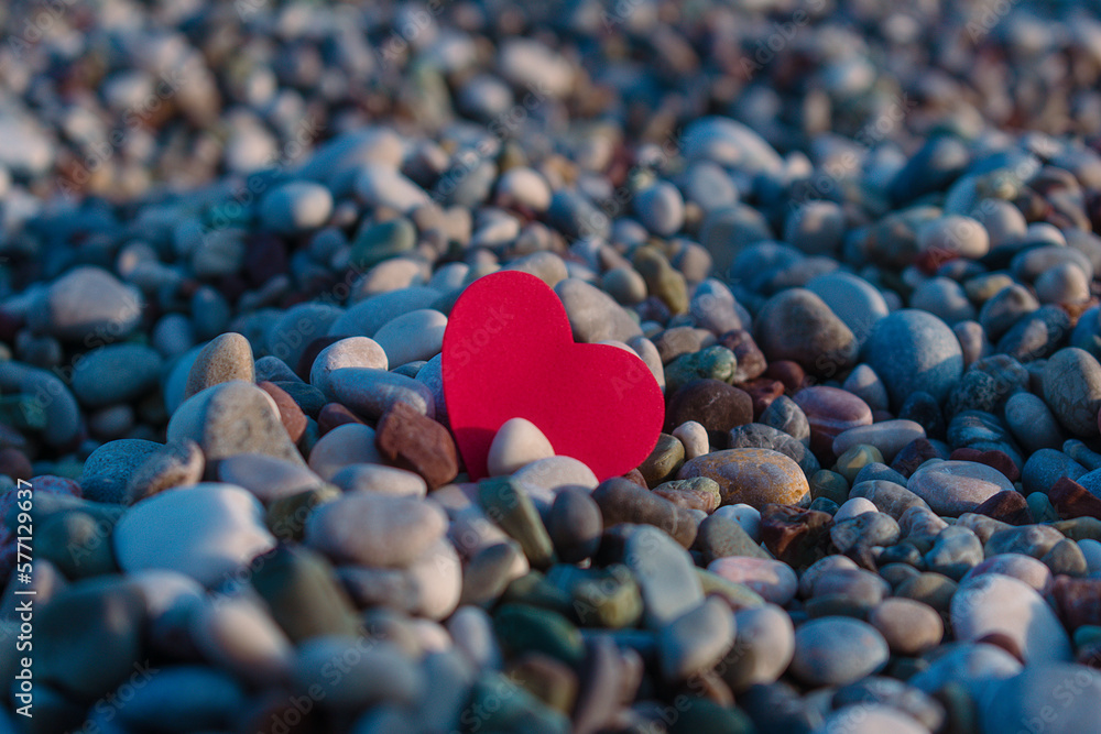 Fototapeta premium Red heart among sea pebbles.