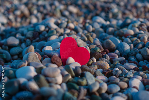 Red heart among sea pebbles.