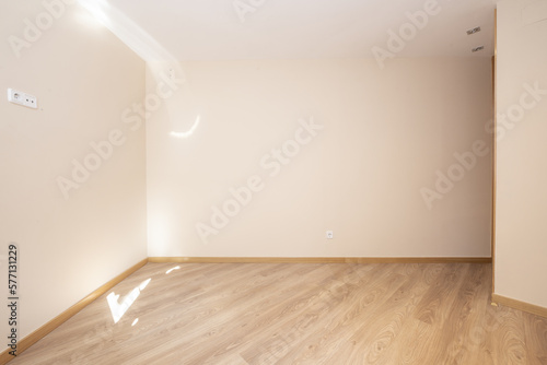 Empty living room of a house with floating wood flooring with cream colored walls