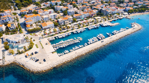 Croatia's harbor is a sight to behold from above. This breathtaking aerial view captures the colorful landscape filled with sailboats, motorboats, and luxurious yachts resting in a clear blue bay. Add