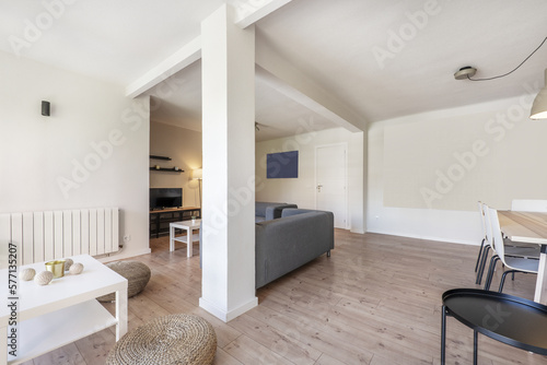 Living room of a holiday rental house with chestnut wood floors with natural fiber poufs  gray fabric sofas and a white square coffee table