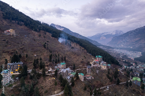 aerial drone landing shot showing lit multi floor story buildings on side of hill at night evening showing hotels shopping areas in manali, shimla himachal