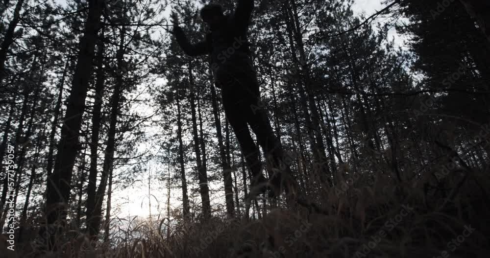 Trail runner in a forest on a cold winter day. Man jumping. Side silhouette view. Sun shining between trees. Recorded at 120 fps. Trail runner in a forest on a cold winter day. Man jumping. Side silhouette view. Sun shining between trees. Recorded at 120 fps.