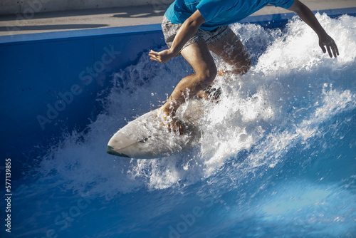 Photography A surfer on his white board surfing in the wave of a swimming pool