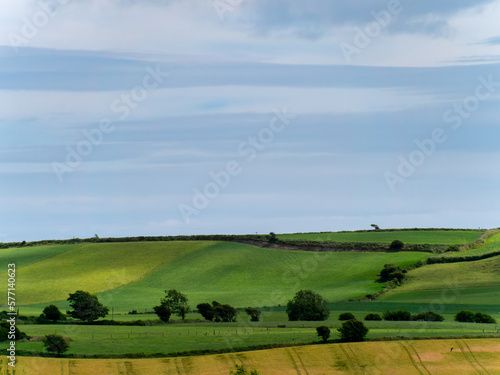 Picturesque agricultural landscape. Green hills, blue sky. Hilly terrain in the south of Ireland, nature.