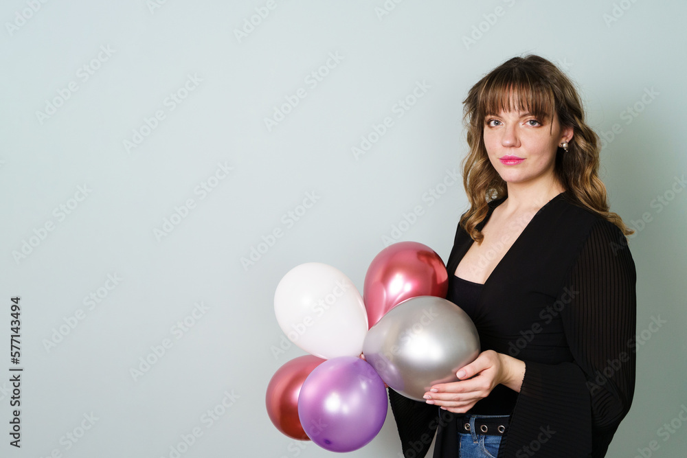 Young Woman Posing and Holding Balloons in Hand Against Grey Background Young Woman Posing and Holding Balloons in Hand Against Grey Background