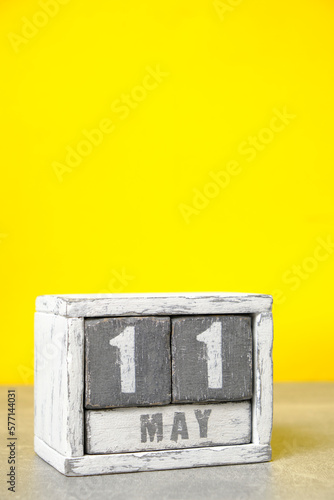 May 11, on calendar made wood painted in gray and white, yellow background. photo