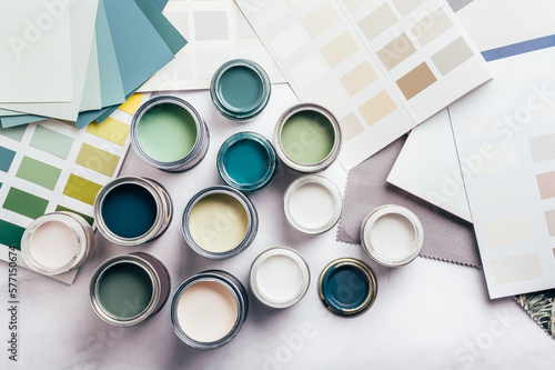 Tiny sample paint cans during house renovation, process of choosing paint for the walls, different green and beige colors, color charts on background photo