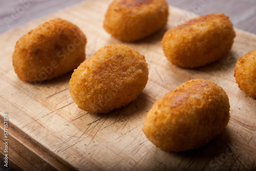 Classic Spanish croquettes on wooden board with dim light in the background. Fried potato. photo