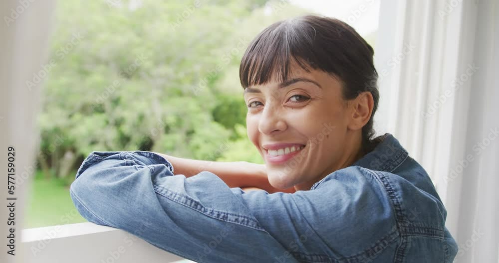 Portrait of happy caucasian woman looking through window and wearing jacket in living room Portrait of happy caucasian woman looking through window and wearing jacket in living room
