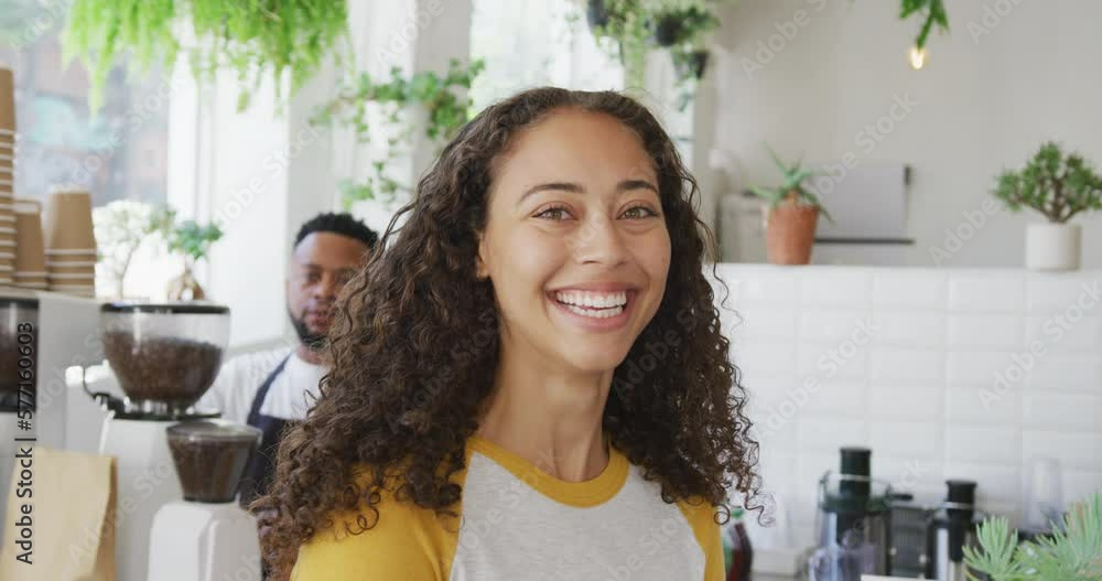 Portrait of happy biracial woman looking at camera and smiling at cafe