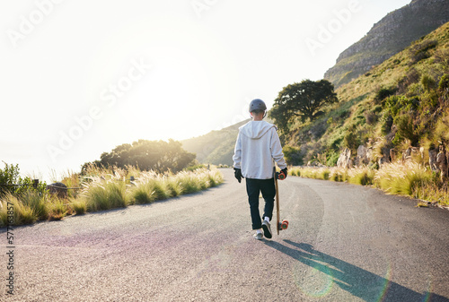 Skateboard  road walking and athlete doing training  exercise and fitness on a hill. Sun  man back and summer sport of a young person ready for balance and freedom from extreme sports with mockup