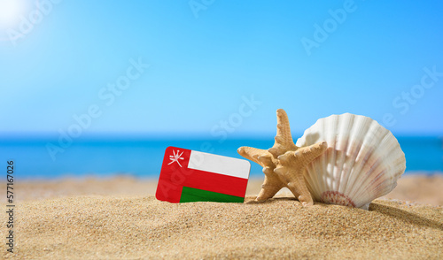 Tropical beach with seashells and flag of Oman. The concept of a paradise vacation on the beaches of the Oman.