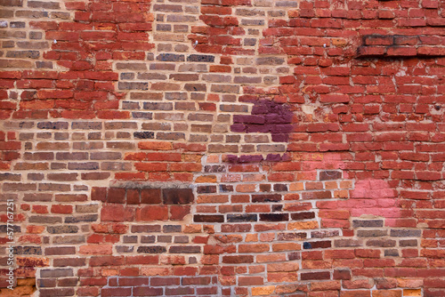 Horizontal view of old wall with patches of different coloured bricks in irregular pattern