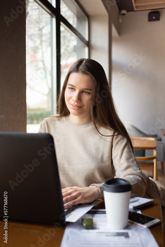 Young woman working with laptop while sitting at cafe indoors