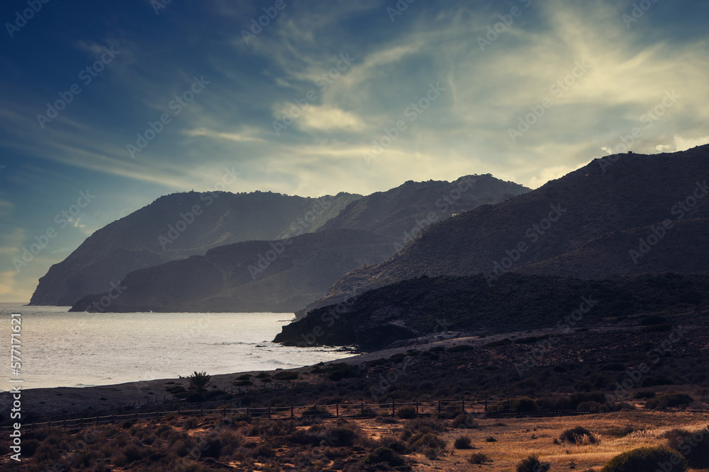 Cliff near the ocean with dramatic sky and sun rays at background Cliff near the ocean with dramatic sky and sun rays at background