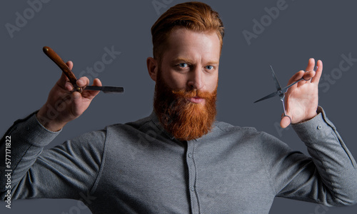 bearded barber man in barbershop studio. barber man hold scissors and blade at barbershop.