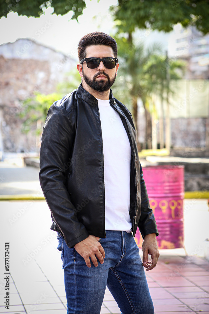 Attractive man with dark glasses looking at camera in cityscape. Man in cityscape with space for text. 