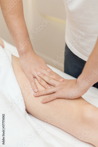Professional masseur make remedial body massage to a Woman's body lying face down on massage table in spa salon