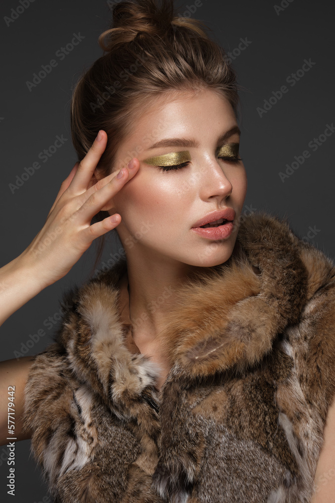 Portrait of a beautiful woman in a furcoat with creative gold makeup in a fashion style. Beauty face. Portrait of a beautiful woman in a furcoat with creative gold makeup in a fashion style. Beauty face.