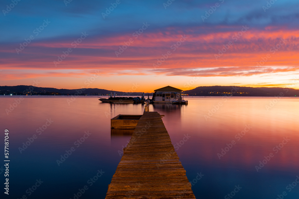 Jetty and small hut with colorful dawn sky.