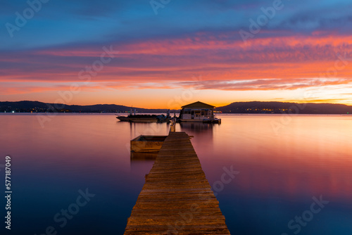 Jetty and small hut with colorful dawn sky.